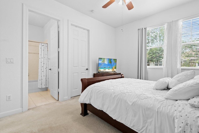 bedroom with a ceiling fan, light carpet, and ensuite bathroom