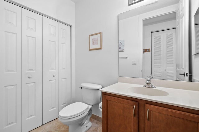 bathroom with toilet, vanity, a closet, and tile patterned floors