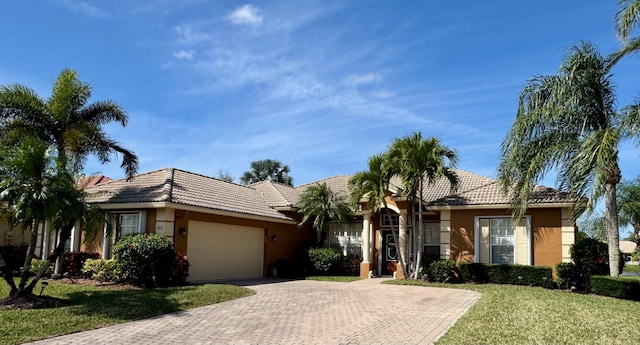 single story home with an attached garage, a tile roof, a front yard, and stucco siding