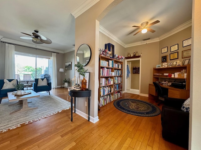 living area with ceiling fan, arched walkways, wood finished floors, baseboards, and crown molding