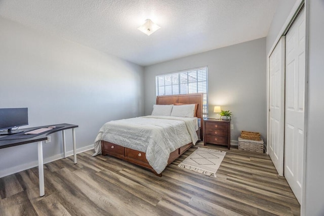 bedroom featuring a textured ceiling, baseboards, dark wood-style flooring, and a closet