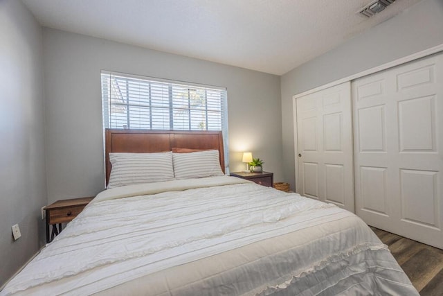 bedroom with a closet, dark wood finished floors, and visible vents