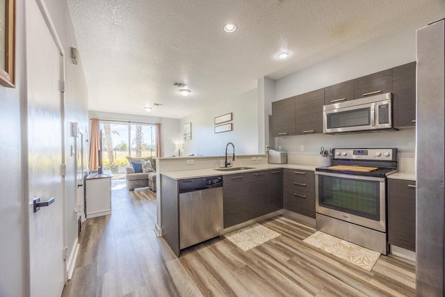 kitchen featuring stainless steel appliances, open floor plan, light countertops, and a peninsula