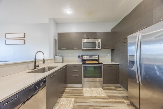 kitchen with modern cabinets, appliances with stainless steel finishes, light countertops, and a sink