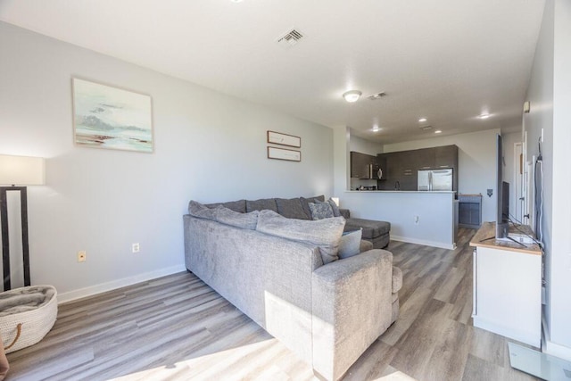 living area with light wood finished floors, recessed lighting, visible vents, and baseboards