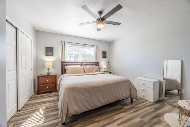 bedroom featuring a textured ceiling, a closet, wood finished floors, and a ceiling fan