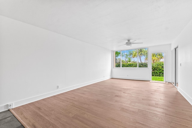 spare room featuring a ceiling fan, baseboards, and light wood finished floors