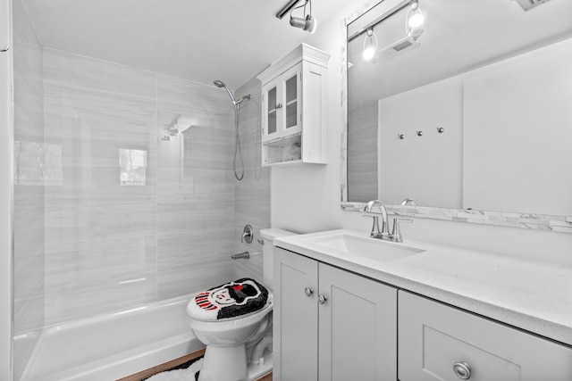 bathroom featuring toilet, visible vents, a tile shower, and vanity