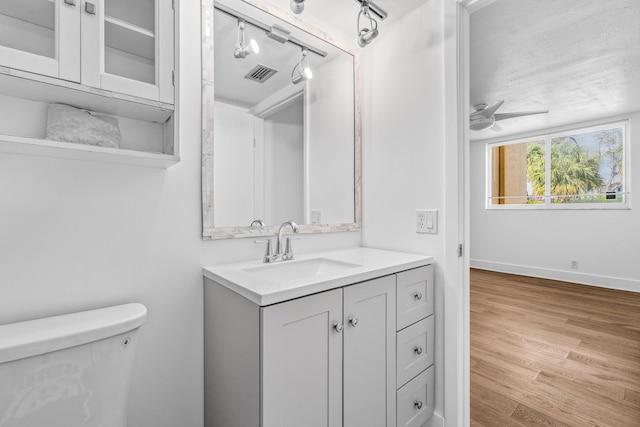 bathroom featuring toilet, wood finished floors, vanity, visible vents, and baseboards