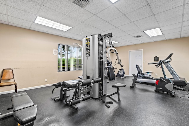 workout area with a paneled ceiling, visible vents, and baseboards