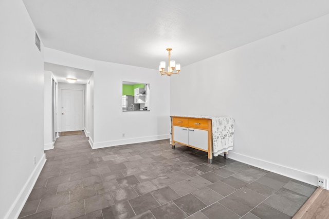 spare room with visible vents, baseboards, and an inviting chandelier