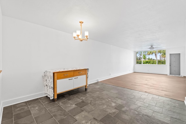 interior space featuring baseboards and ceiling fan with notable chandelier