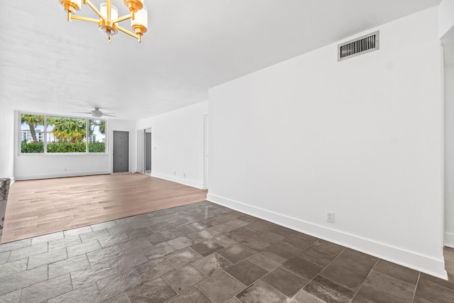 unfurnished living room with ceiling fan with notable chandelier, dark wood-style flooring, visible vents, and baseboards