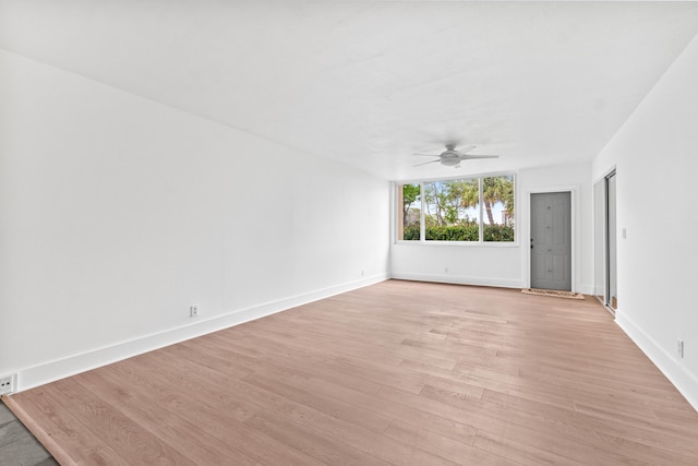 unfurnished room with light wood-type flooring, a ceiling fan, and baseboards