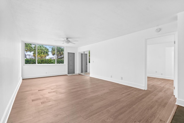 empty room with baseboards, ceiling fan, and light wood-style floors