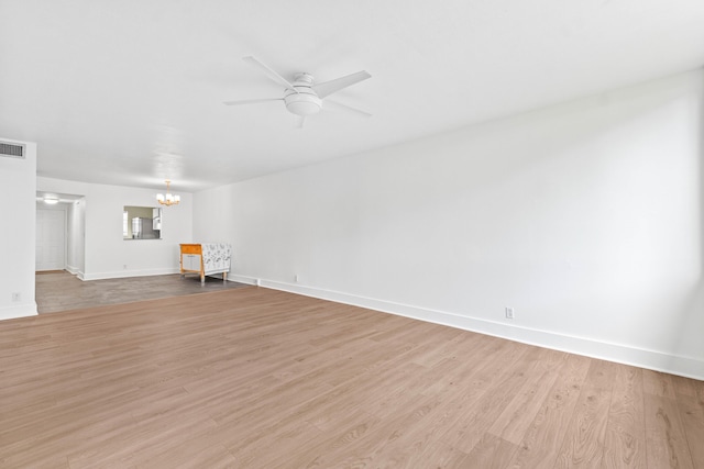 unfurnished living room with ceiling fan with notable chandelier, light wood-type flooring, visible vents, and baseboards