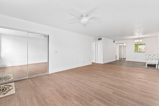 unfurnished living room featuring visible vents, baseboards, wood finished floors, and ceiling fan with notable chandelier