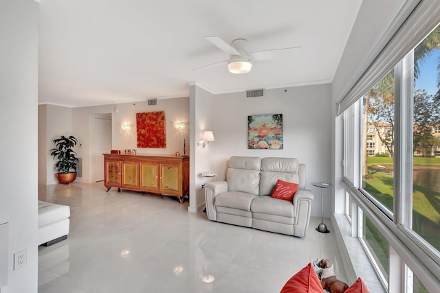 living area featuring a ceiling fan, visible vents, and crown molding