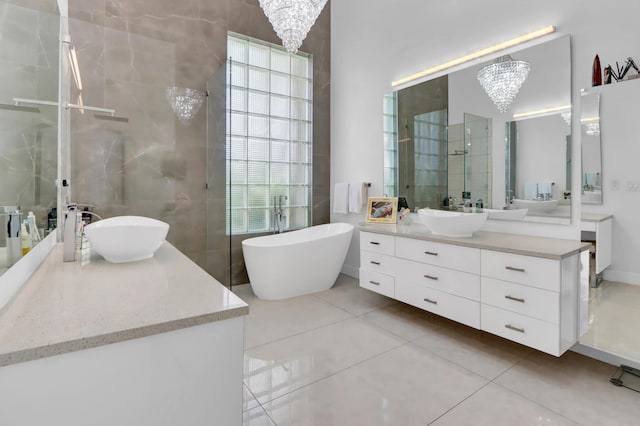 full bathroom featuring a chandelier, a freestanding bath, vanity, and tile patterned floors