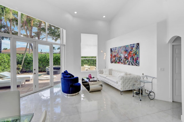 tiled living room with arched walkways, a towering ceiling, and recessed lighting