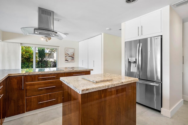 kitchen featuring visible vents, island exhaust hood, stainless steel refrigerator with ice dispenser, white cabinetry, and black electric cooktop