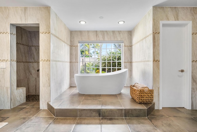 bathroom featuring a soaking tub, tile walls, and walk in shower