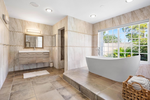 bathroom with vanity, tile walls, walk in shower, and a freestanding bath