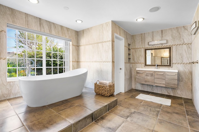 full bath with vanity, tile walls, a soaking tub, and recessed lighting