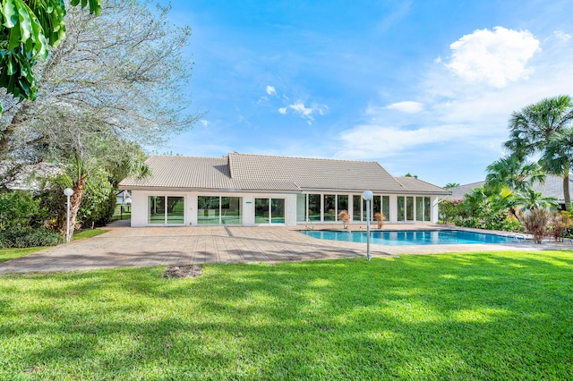 rear view of house featuring a tiled roof, stucco siding, a yard, an outdoor pool, and a patio