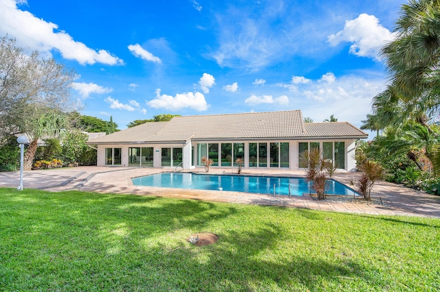 rear view of property featuring an outdoor pool, a yard, a patio area, and a tiled roof