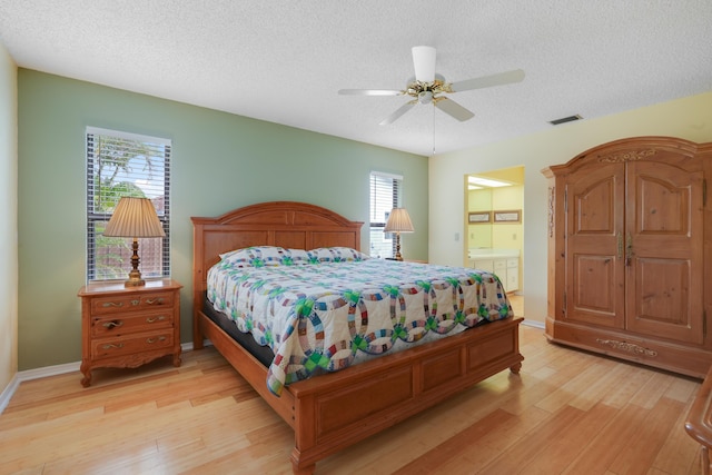 bedroom featuring visible vents, light wood-style flooring, a textured ceiling, and multiple windows