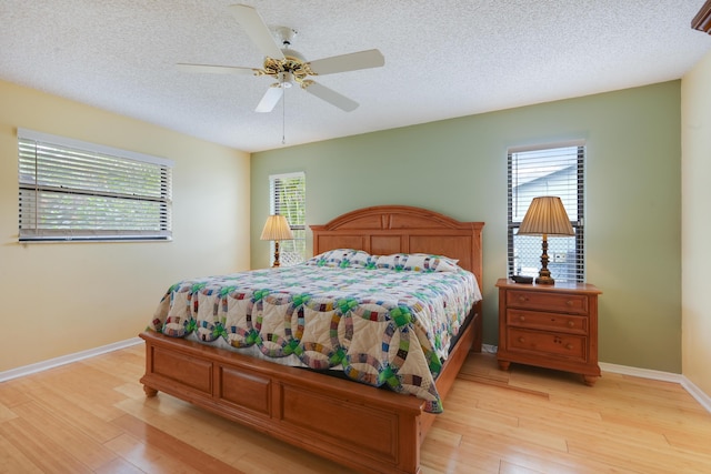 bedroom featuring light wood-type flooring, baseboards, and a textured ceiling