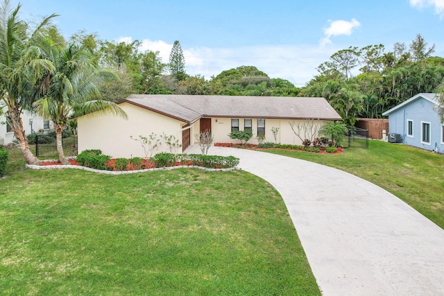 view of front facade with concrete driveway, a front yard, fence, and stucco siding