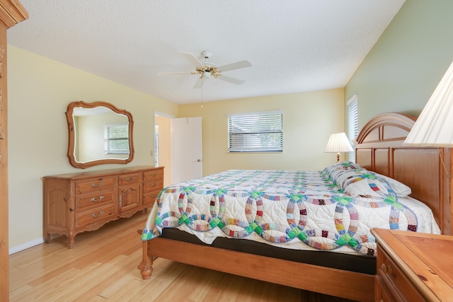 bedroom featuring light wood-type flooring, a ceiling fan, and a textured ceiling