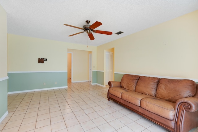 unfurnished living room with ceiling fan, a textured ceiling, visible vents, and baseboards