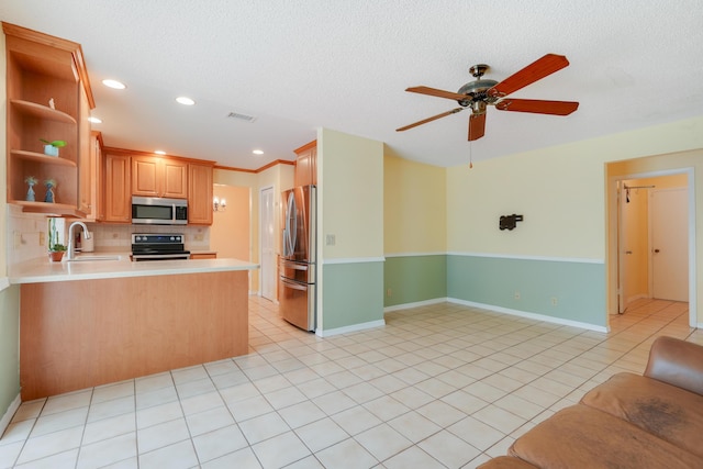 kitchen with decorative backsplash, a peninsula, stainless steel appliances, light countertops, and a sink