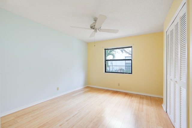 unfurnished bedroom with a textured ceiling, ceiling fan, light wood-style flooring, baseboards, and a closet