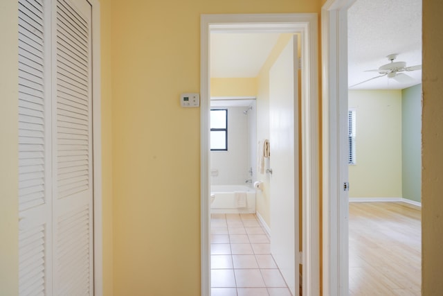 hallway featuring light tile patterned flooring and baseboards