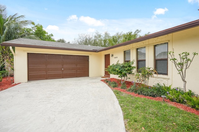 single story home with a front lawn, driveway, an attached garage, and stucco siding