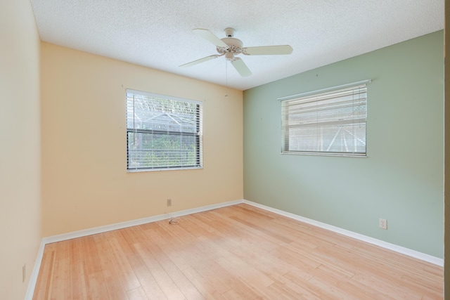 spare room with baseboards, ceiling fan, light wood-style flooring, and a textured ceiling