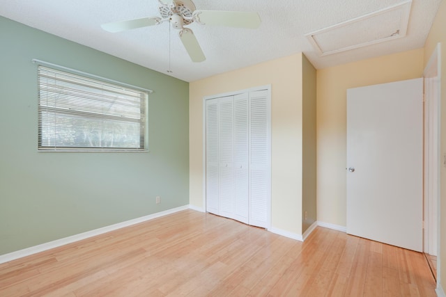 unfurnished bedroom with light wood-style floors, attic access, baseboards, and a closet