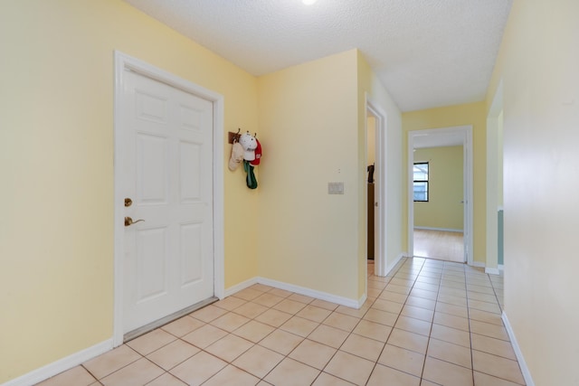 foyer entrance featuring light tile patterned floors, baseboards, and a textured ceiling