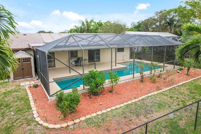 rear view of property with glass enclosure, a patio, a storage shed, an outdoor pool, and stucco siding