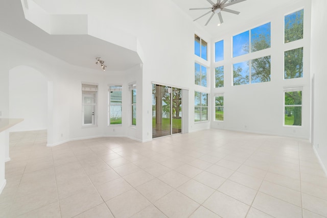 unfurnished room with a healthy amount of sunlight, light tile patterned floors, baseboards, and a ceiling fan