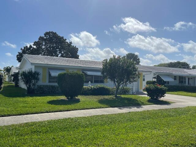 ranch-style house featuring driveway, an attached garage, and a front lawn