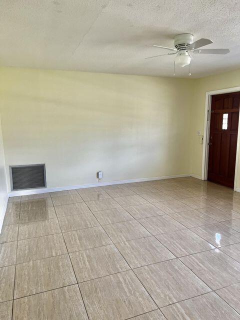 empty room featuring a textured ceiling, a ceiling fan, visible vents, and baseboards