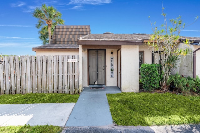 entrance to property with fence and stucco siding