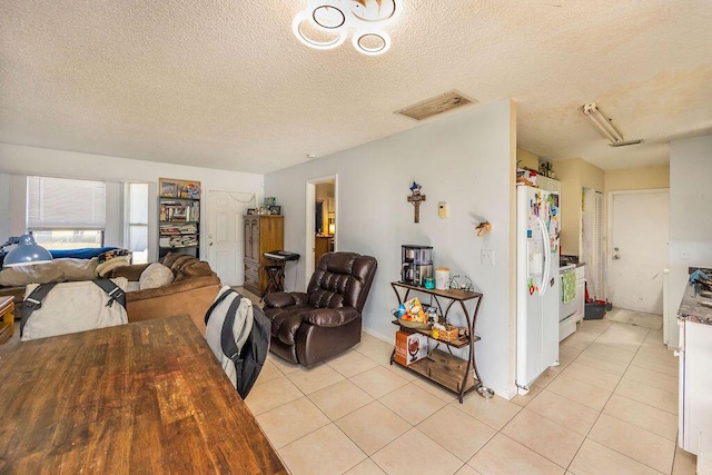 interior space with a textured ceiling, light tile patterned flooring, and visible vents