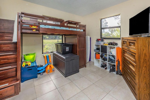 bedroom featuring light tile patterned floors, multiple windows, and a textured ceiling