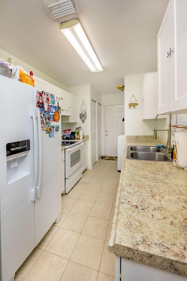 kitchen featuring white appliances, washer / clothes dryer, light countertops, white cabinetry, and a sink